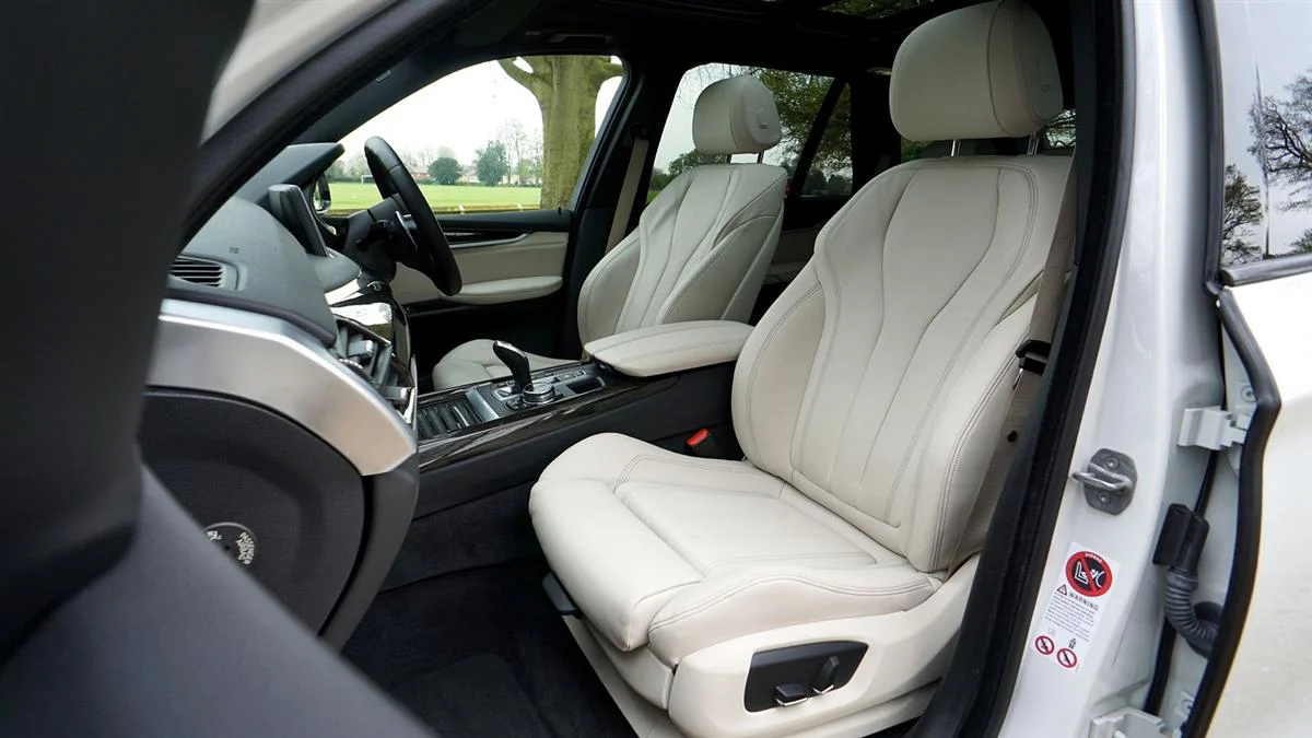 The pale leather cabin of a large SUV with the door open