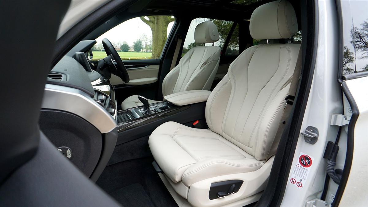 The pale leather cabin of a large SUV with the door open