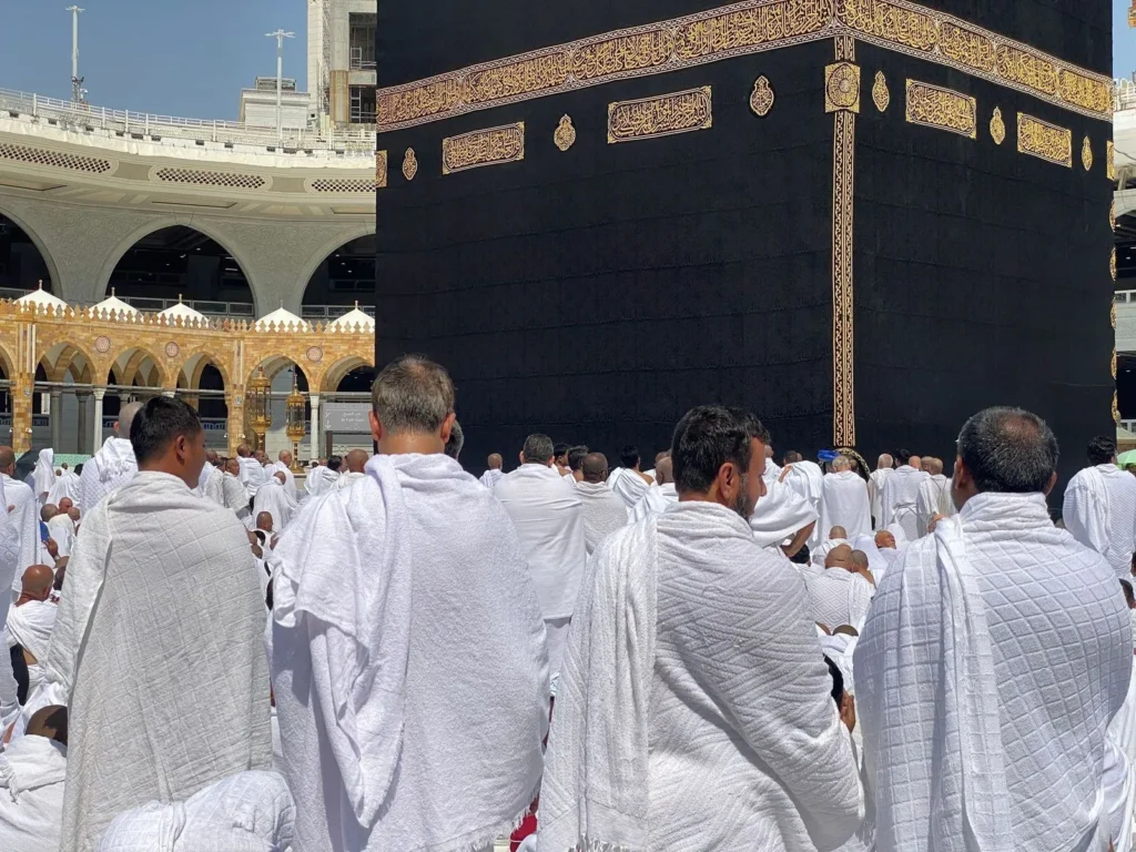 Men in ihram seen from behind, facing the Kaaba in Masjid al-Haram