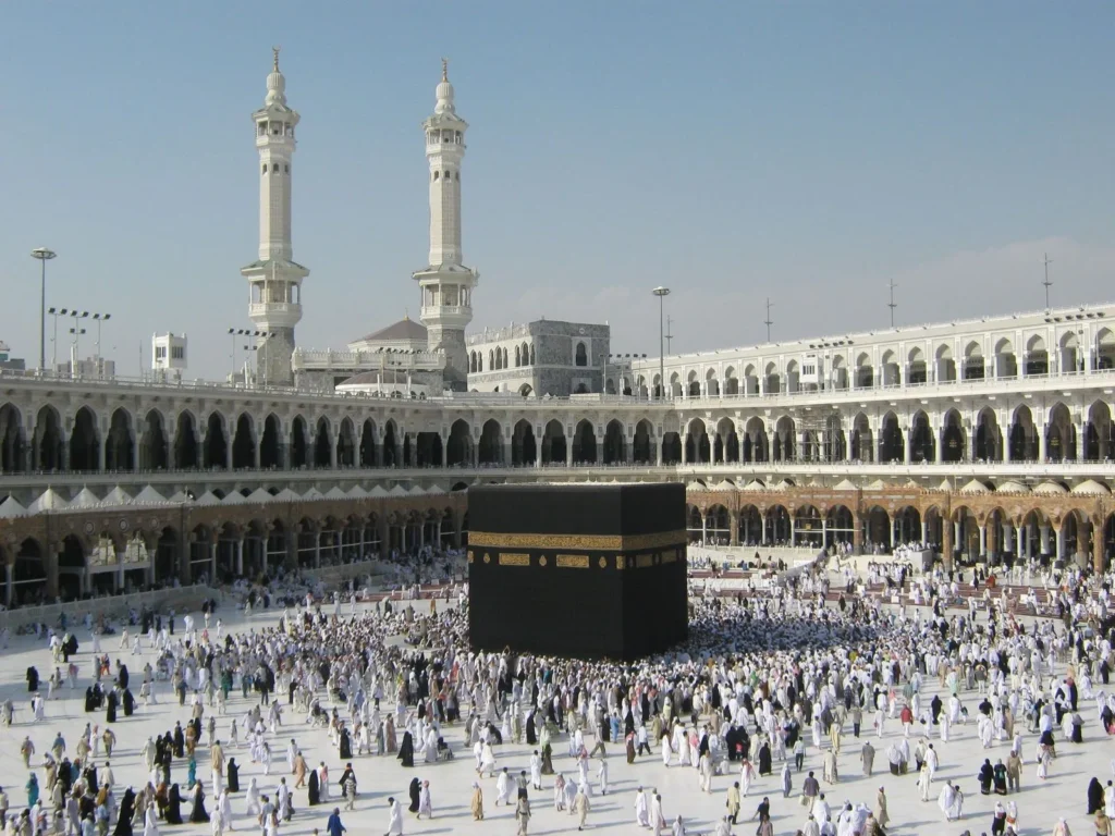 The Kaaba in Masjid al-Haram in daylight, with minarets behind