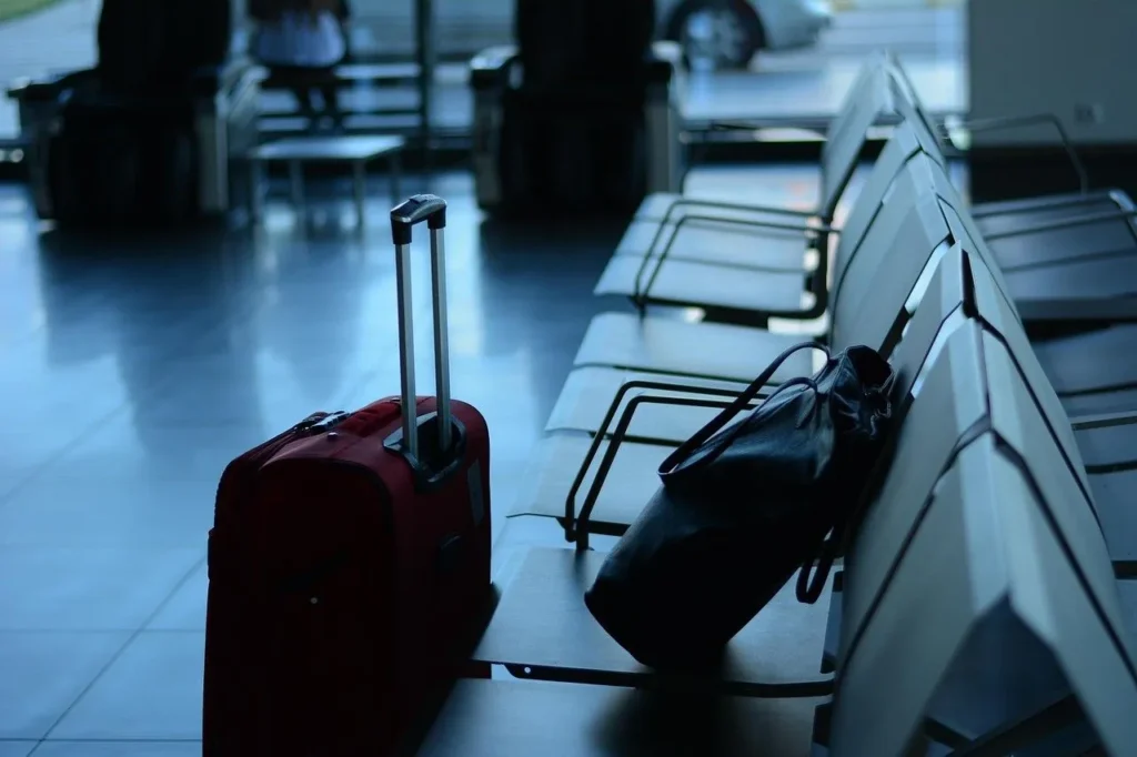 A suitcase and a bag beside a row of terminal seats