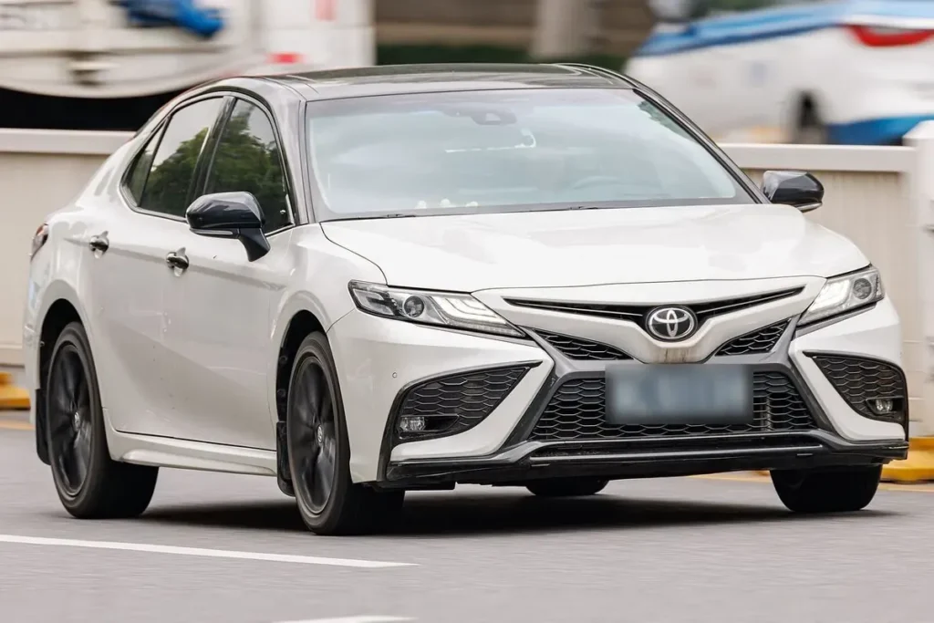 A white Toyota Camry, front three quarter view