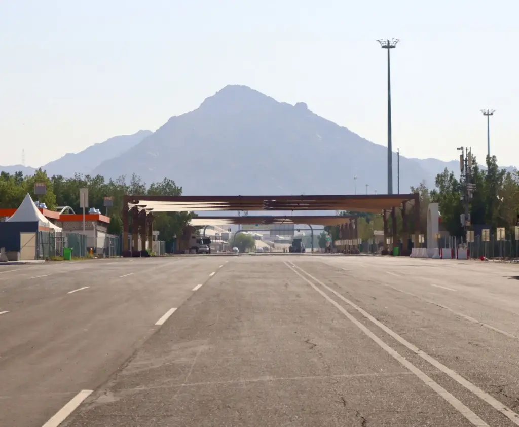 An empty road leading toward a rocky mountain peak