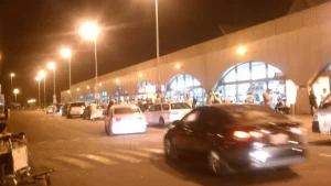 Kerbside outside King Abdulaziz International Airport, Jeddah, at night with cars and travellers at the doors