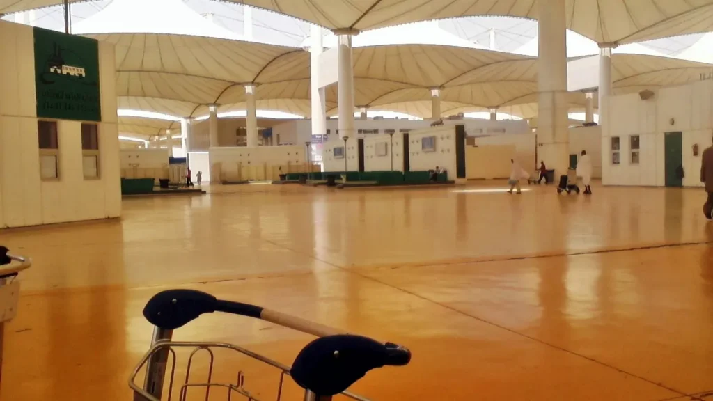 Empty plaza under the tent roof of the Hajj Terminal, Jeddah airport, with a luggage trolley in the foreground
