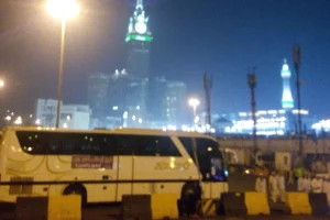 Coach parked at night with the Makkah Clock Royal Tower lit up behind