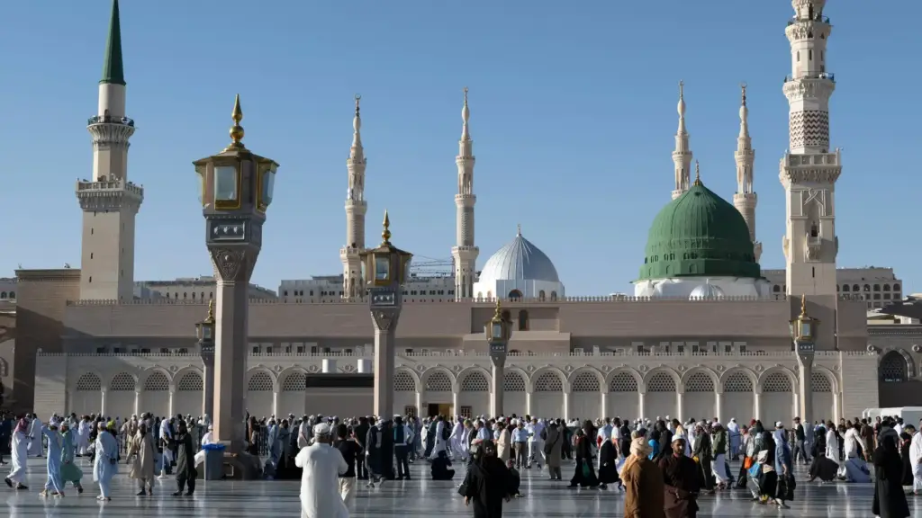 People in the courtyard of Masjid an-Nabawi, Madinah, with the Green Dome and minarets