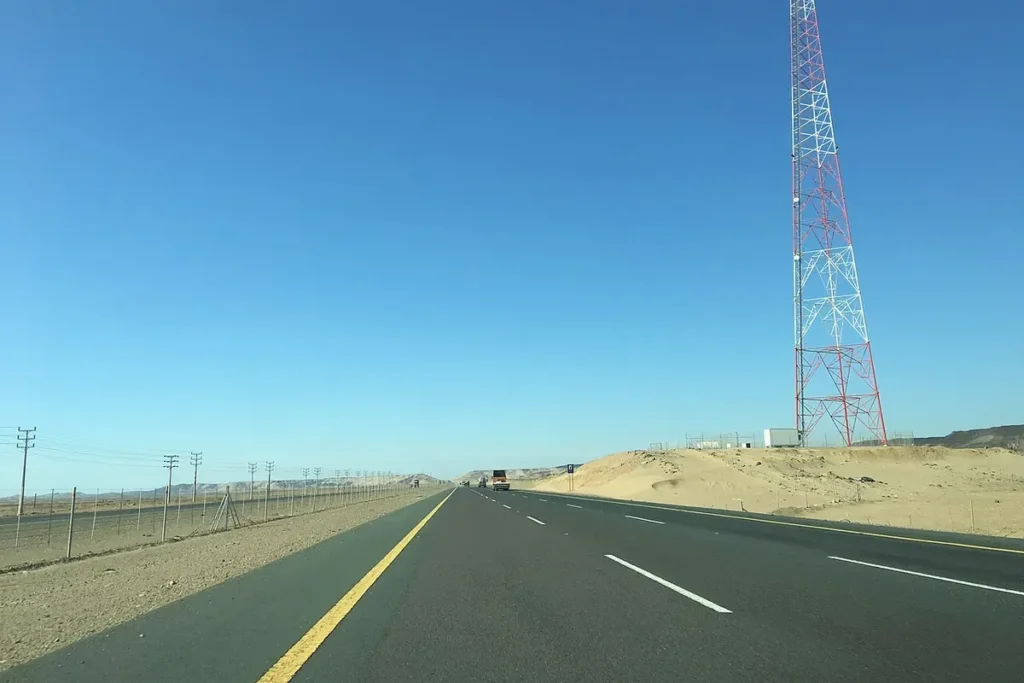 Straight desert highway in Makkah Province with a telecom mast beside the road, geotagged north of Jeddah