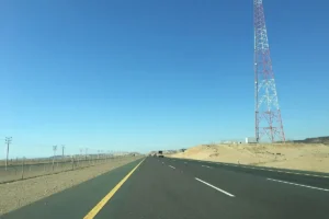Straight desert highway in Makkah Province with a telecom mast beside the road, geotagged north of Jeddah