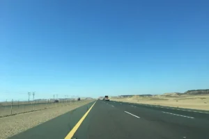 Straight desert highway in Makkah Province under a clear blue sky, geotagged north of Jeddah