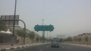 Green sign reading Mina Ends Here in Arabic and English over a road leaving Mina, Makkah