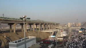 Mina during Hajj: Mashaer metro line on its viaduct, pilgrims on the road and service buildings