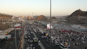 Roads in Mina during Hajj with buses, vans and pilgrims on foot at dusk