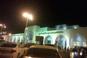 Arrivals building of Prince Mohammad bin Abdulaziz Airport, Madinah, at night with its Arabic name and cars in front