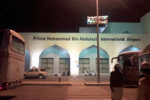 Old terminal of Prince Mohammad bin Abdulaziz International Airport, Madinah, at night, with coaches waiting at the front