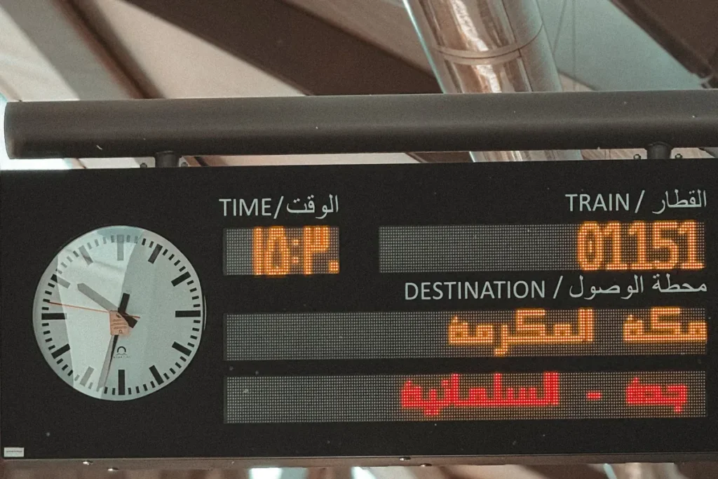 Haramain railway information board in Arabic and English showing a train to Makkah calling at Jeddah Al Sulaymaniyah; the station where it hangs is not named