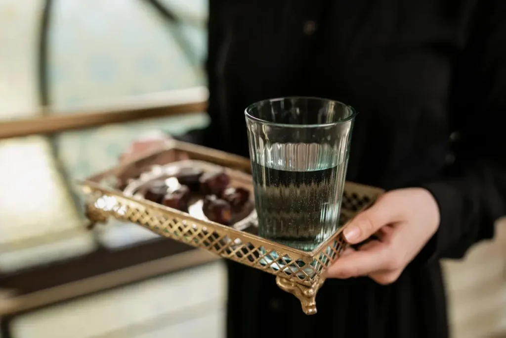 Glass of water and dates offered on a tray