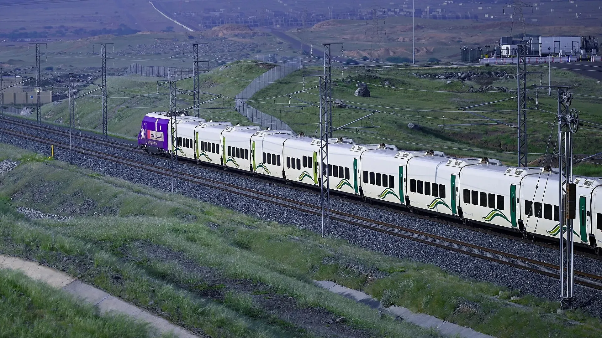 Haramain High Speed Railway train running through green hills in the Hijaz