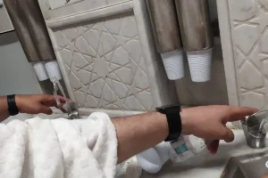 Zamzam water taps with cups at a Zamzam drinking point in Masjid al-Haram, Makkah, hands only