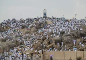 Jabal al-Rahmah at Arafat covered with pilgrims in white, the white pillar on the summit