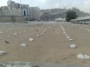 Lines of small stone grave markers across the sandy ground of Jannat al-Mualla