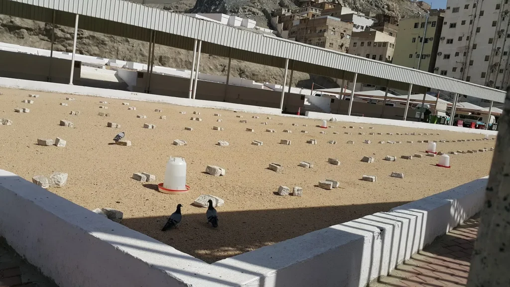 Rows of simple unmarked graves inside Jannat al-Mualla cemetery in Makkah, with a shaded walkway