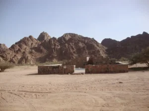 A stone shelter on the open sand of Wadi al-Jinn below the mountains