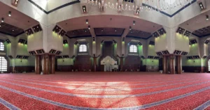 The wide prayer hall inside Masjid Aisha at Taneem with its red carpet