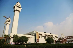 Masjid Aisha at Taneem in Makkah, white walls and two tall minarets behind gardens