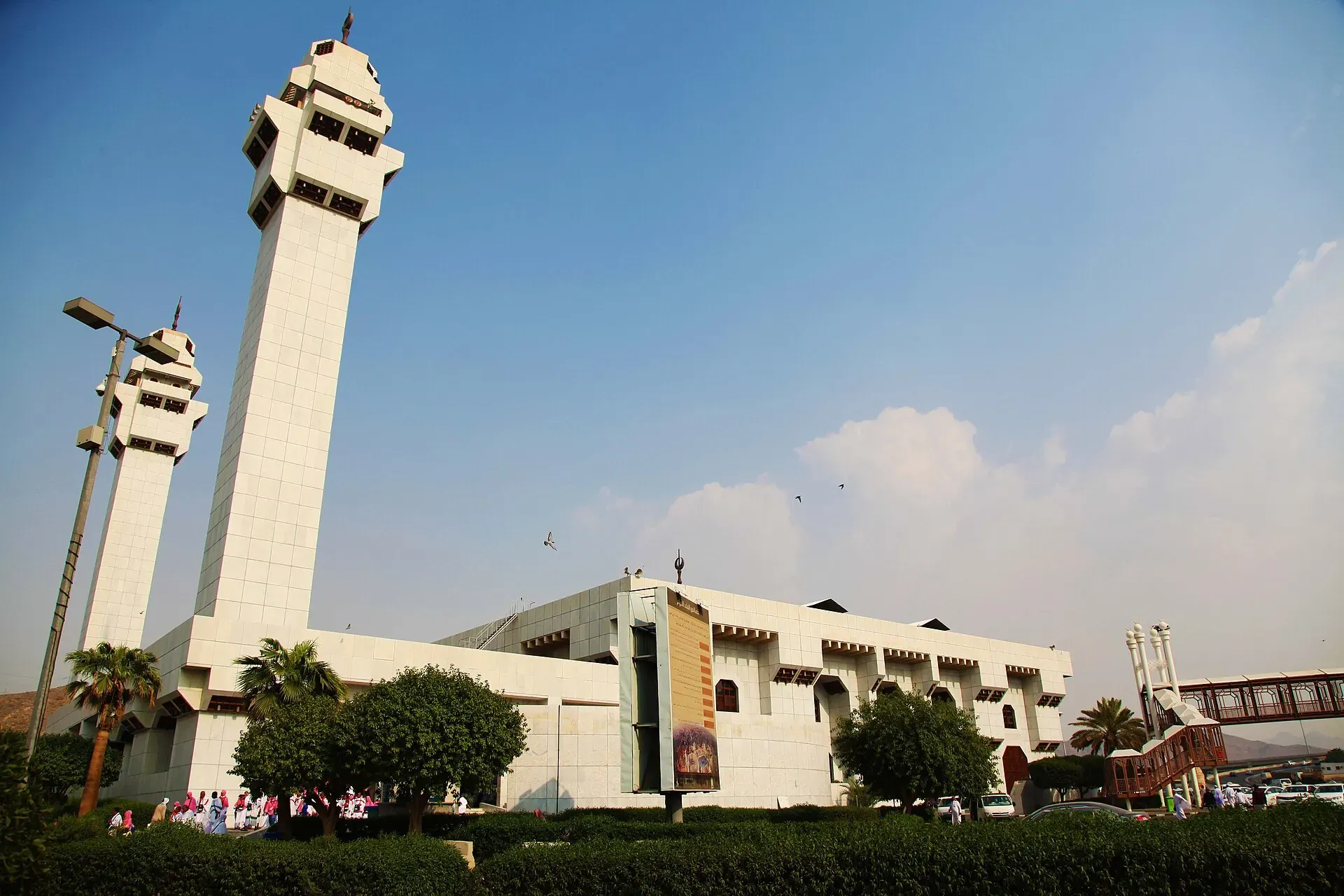 Masjid Aisha at Taneem in Makkah, white walls and two tall minarets behind gardens