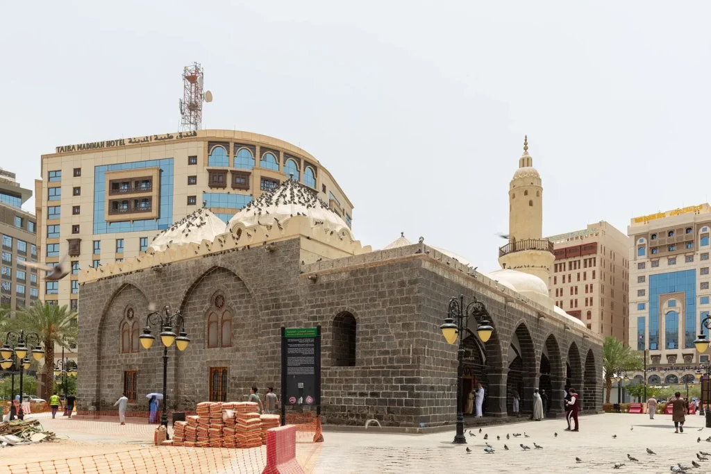 Masjid al-Ghamama in Madinah, black stone walls and white domes, on the plaza near Masjid an-Nabawi