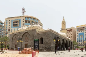Masjid al-Ghamama in Madinah, black stone walls and white domes, on the plaza near Masjid an-Nabawi