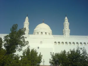 Masjid al-Qiblatayn with its twin minarets and white dome behind trees