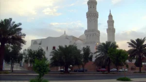 Masjid al-Qiblatayn from the street, two minarets rising above palm trees