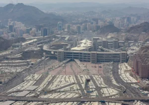 Rows of white tents in Mina with the Jamarat building and the hills of Makkah behind
